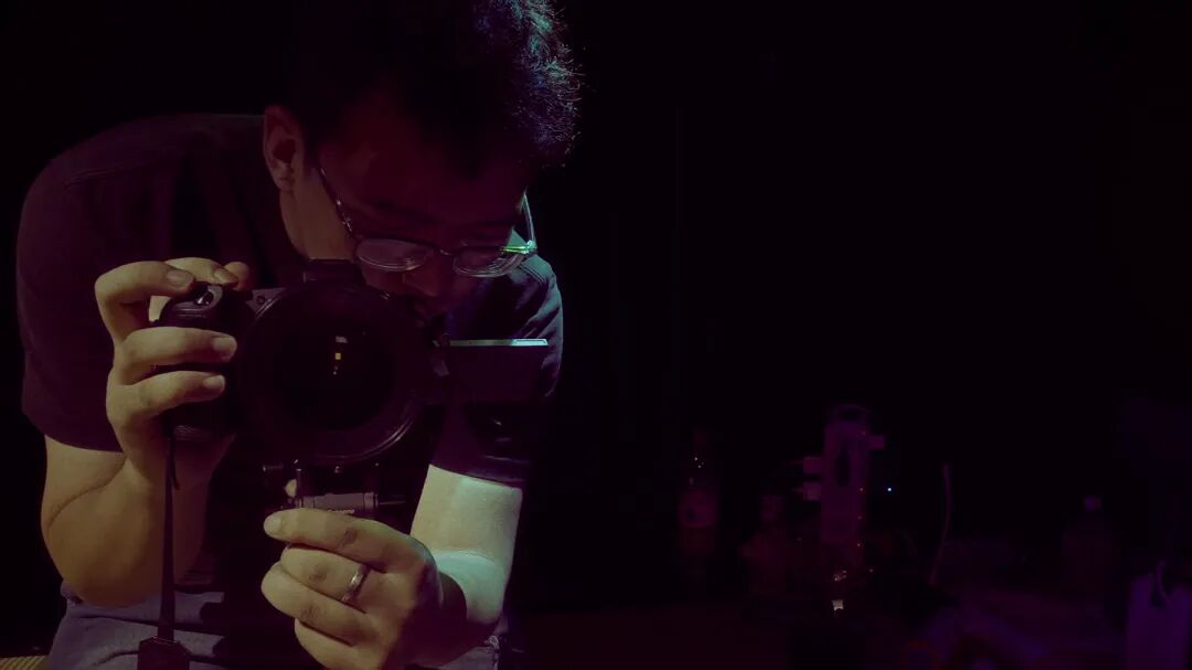 片头持相机者单帧,摄影者在暗场中显影